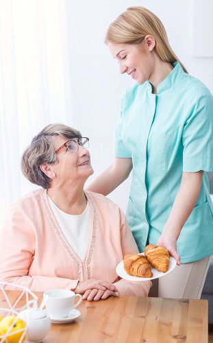 caregiver serving bread to an elderly woman