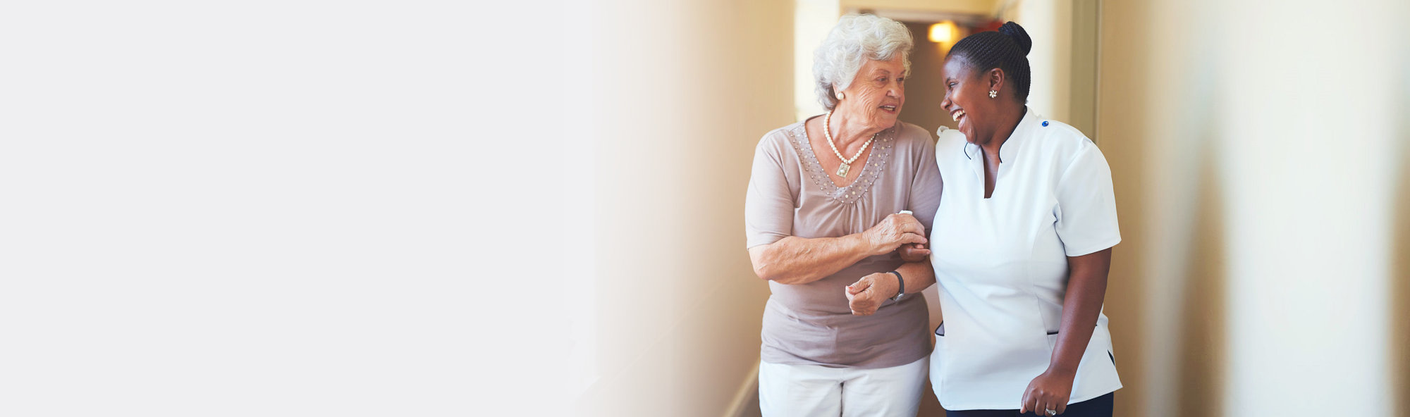 elderly woman in hallway assisted by a caregiver
